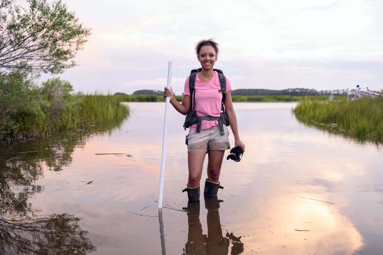 Woman standing in Marsh water holding binoculars